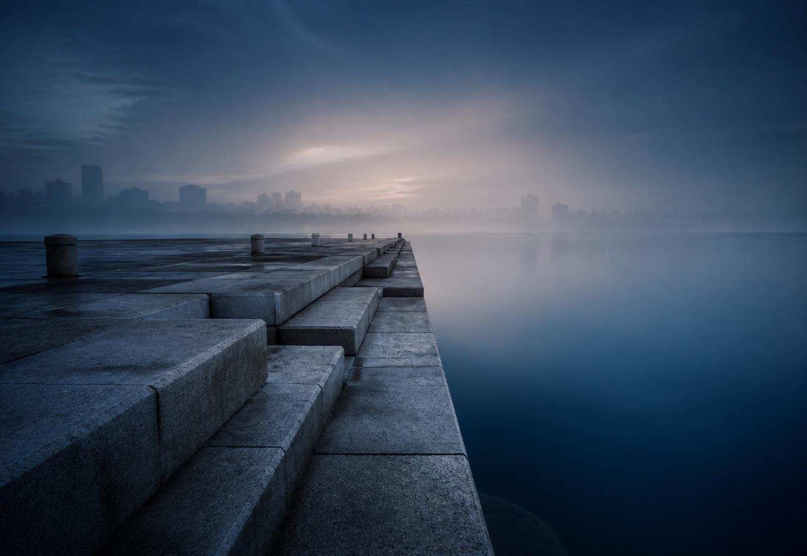 A stone quay meeting still water at dawn
